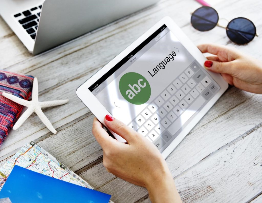 يدان تحملان جهازًا لوحيًا مفتوحًا على تطبيق ترجمة لغات.